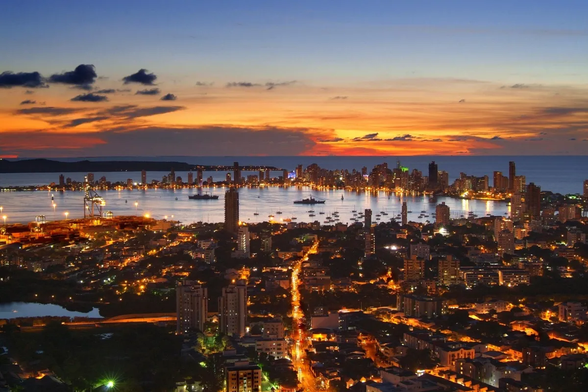 A stunning panoramic aerial view of Cartagena's historic walled city and modern skyline at sunset.