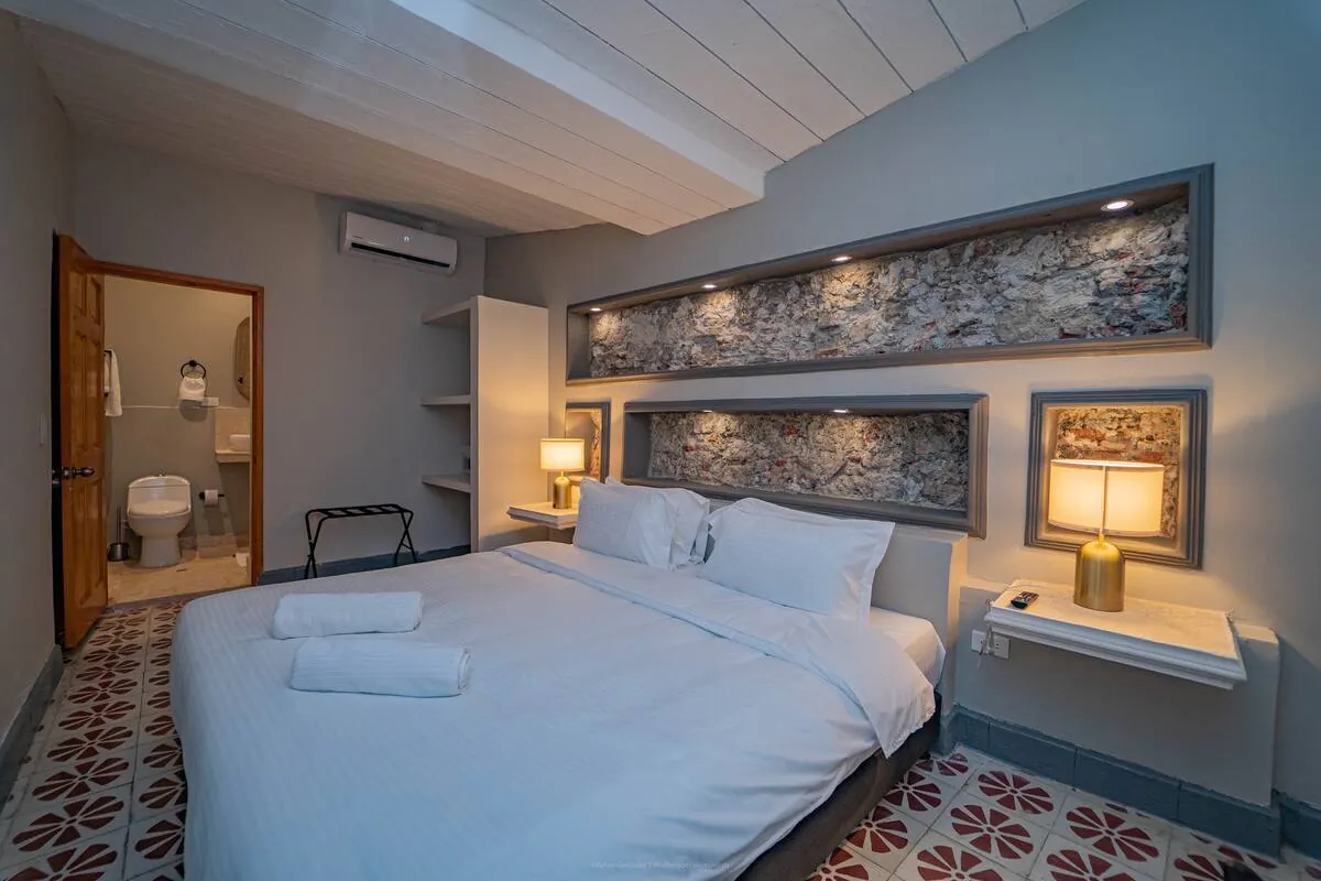 Suite-style bedroom with blue wall, framed art, and private bath view