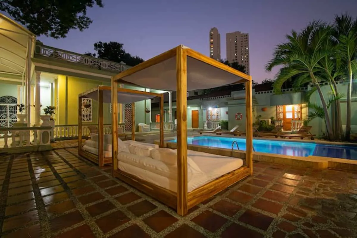 Piscina de patio con daybed de madera y fachada clasica