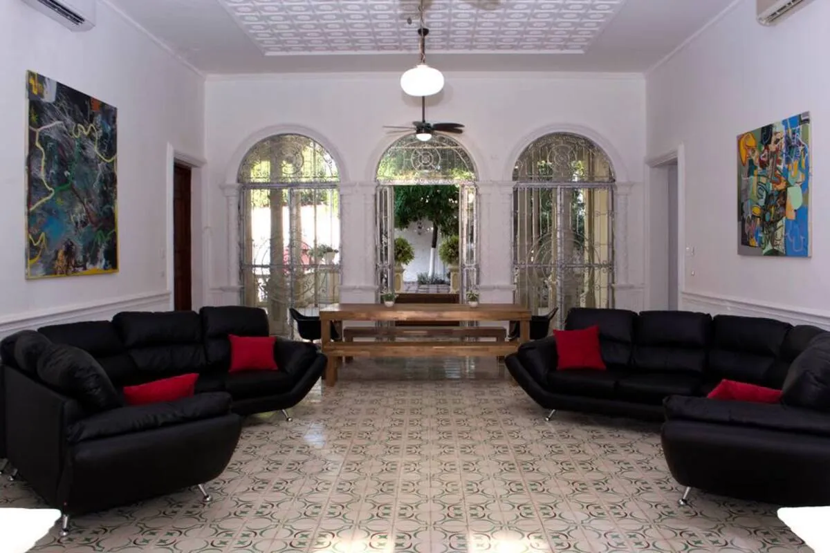 Sala clasica con sofas negros, cojines rojos, ventanas arqueadas y piso de mosaico