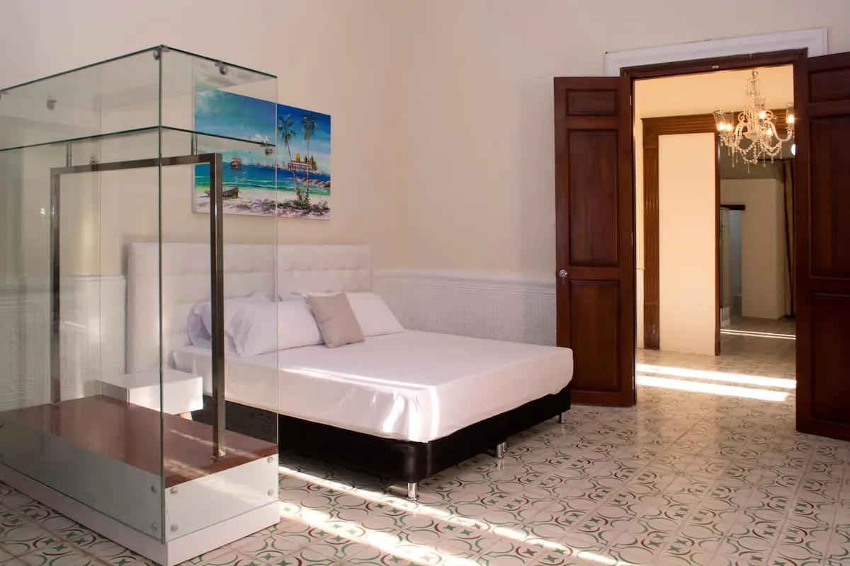 Habitacion con ducha de vidrio y cama blanca