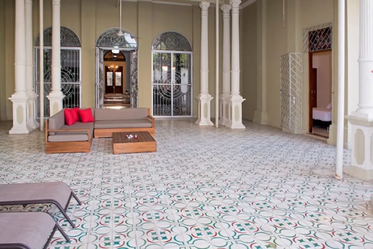 Patio interior con ventanas arqueadas, columnas, asoleadoras y piso de mosaico