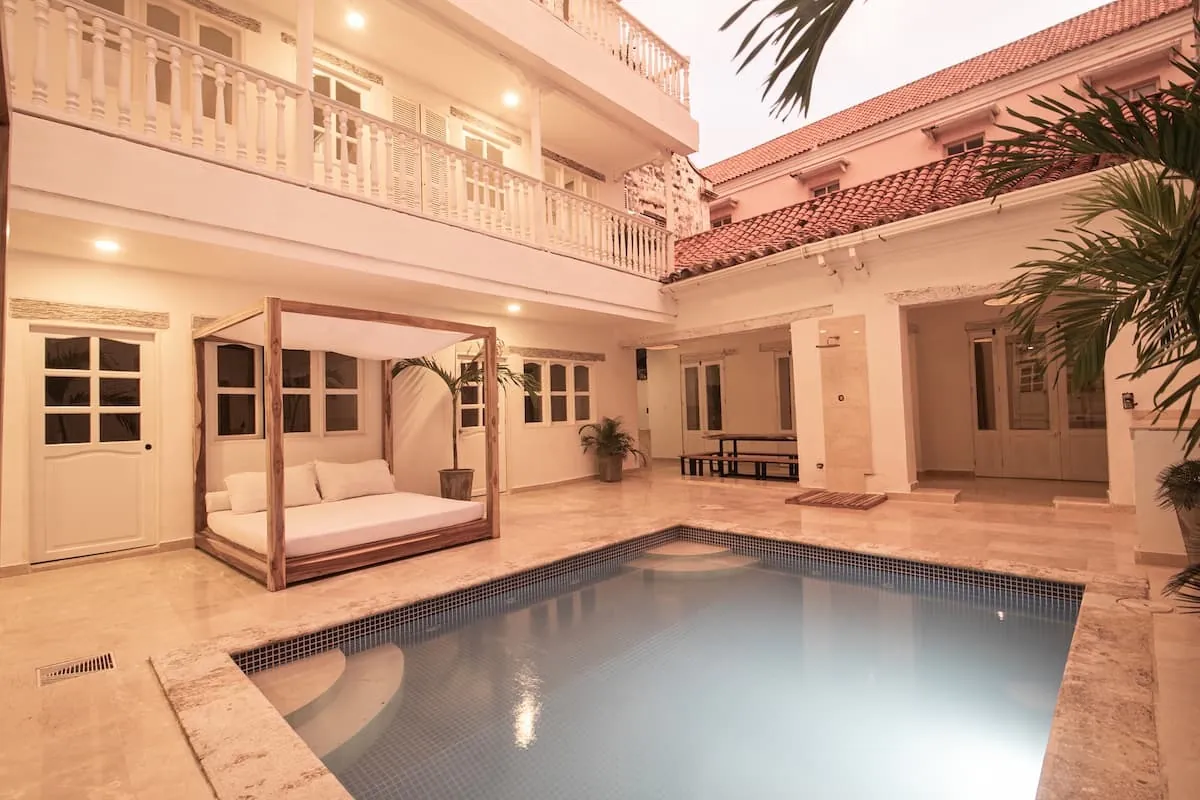 Piscina de patio con daybeds de madera y tejados de Cartagena