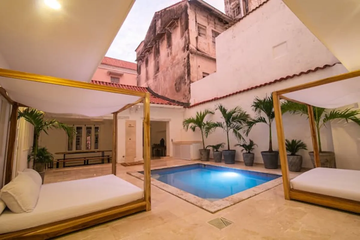 Patio de piscina con daybed con dosel y palmeras