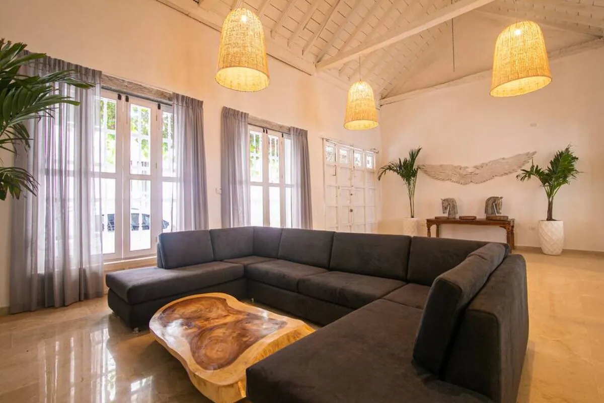Sala luminosa con sofa seccional negro y ventanas altas