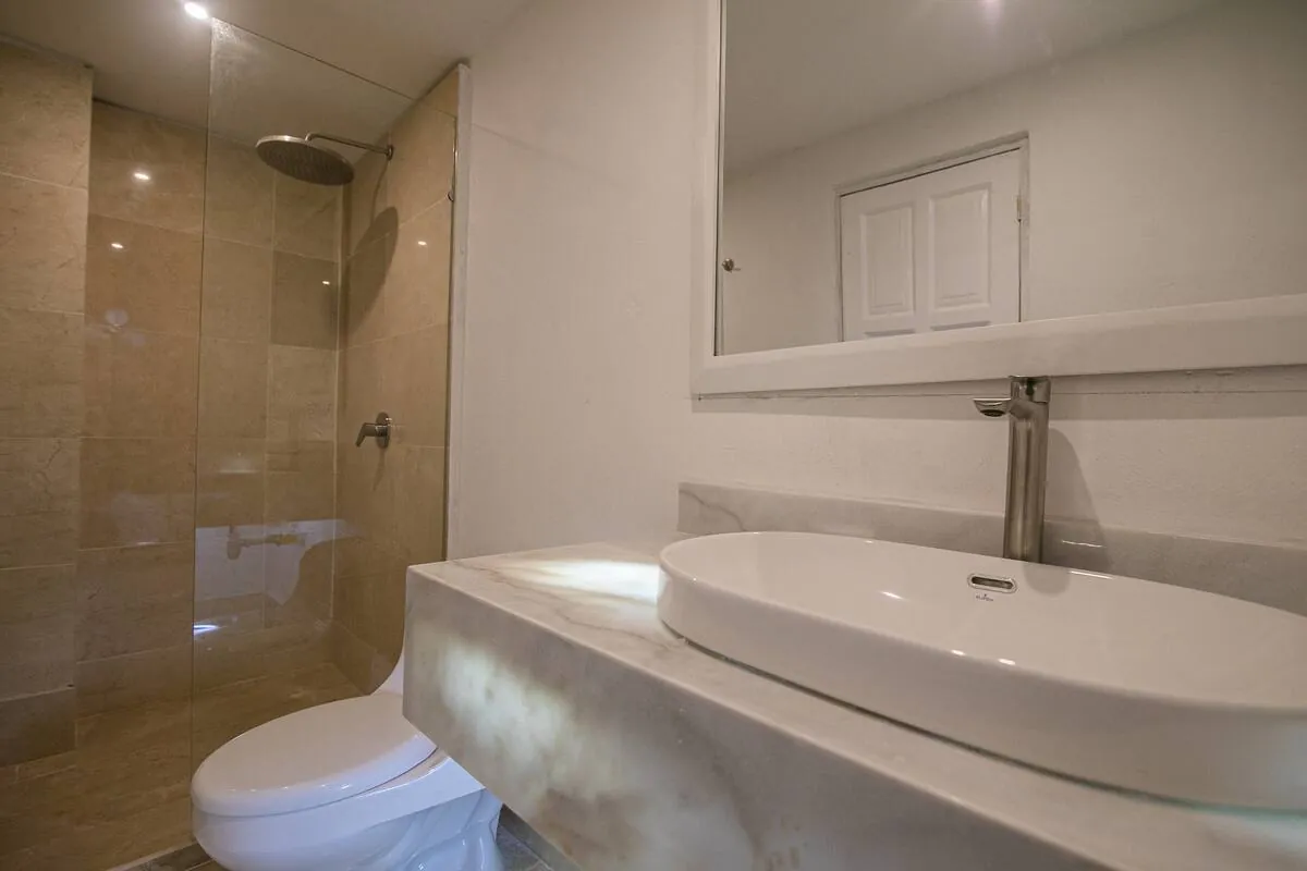 Bano de marmol con lavamanos ovalado y ducha de vidrio