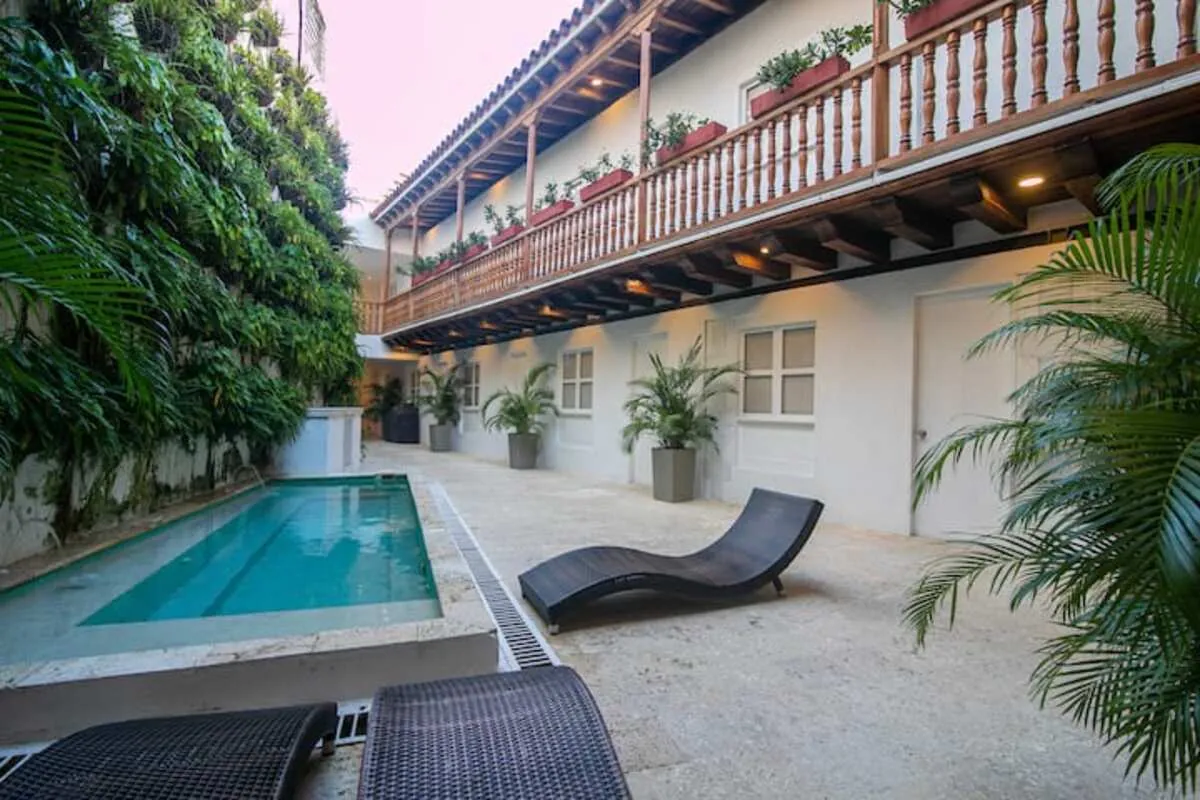 Long courtyard pool with black loungers and upper-level wood balcony