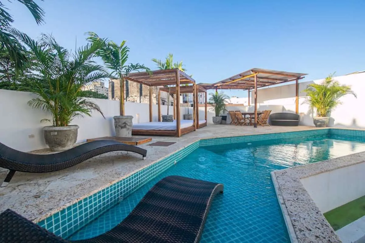 Blue-tile rooftop pool with curved loungers and palms