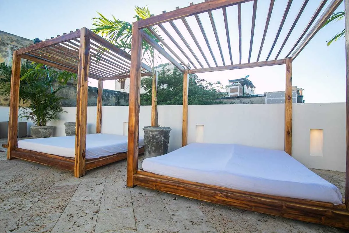 Rooftop daybeds under wood pergolas beside the pool terrace
