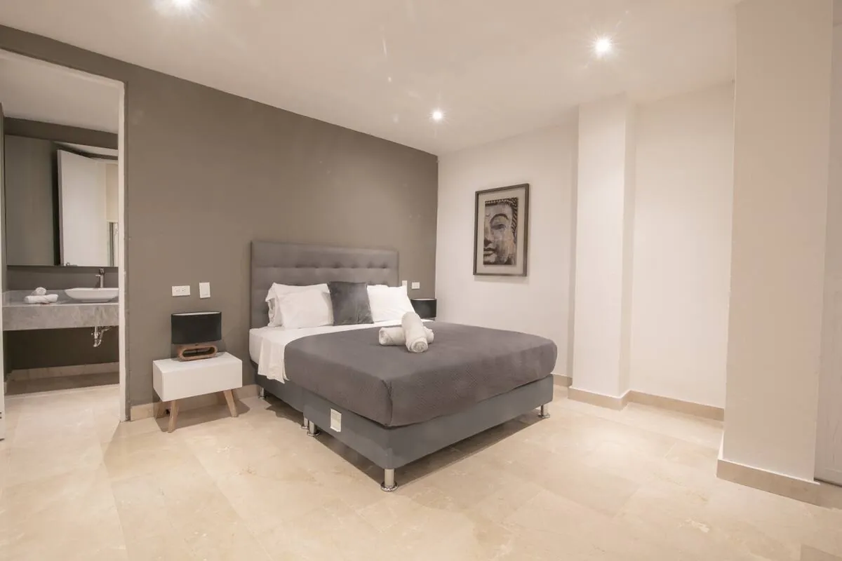 Neutral en-suite bedroom with grey bed and open bathroom entry