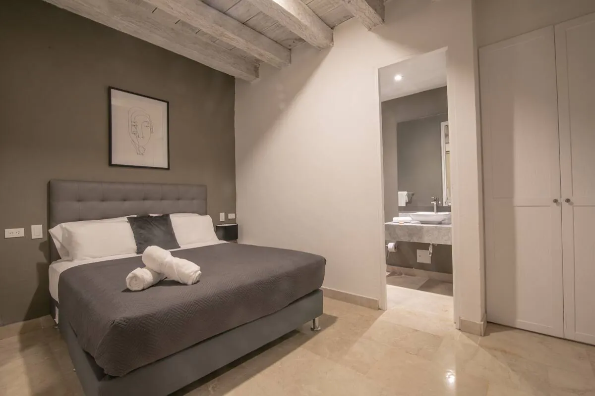 Neutral bedroom with grey bed, closet wall, and private bath entry