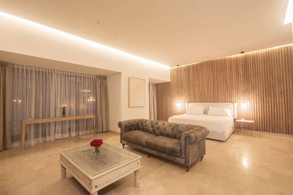 Large suite lounge with leather sofa, wall TV, and warm wood backdrop