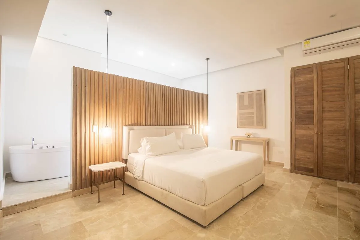 Bedroom with white bed, wood-slat wall, and soft pendant lighting