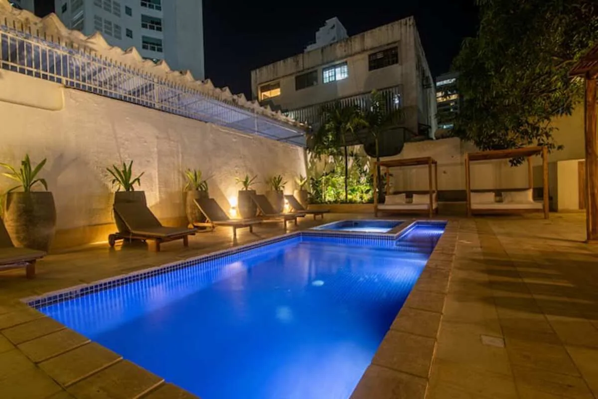 Private pool with wood deck, loungers, and garden lighting