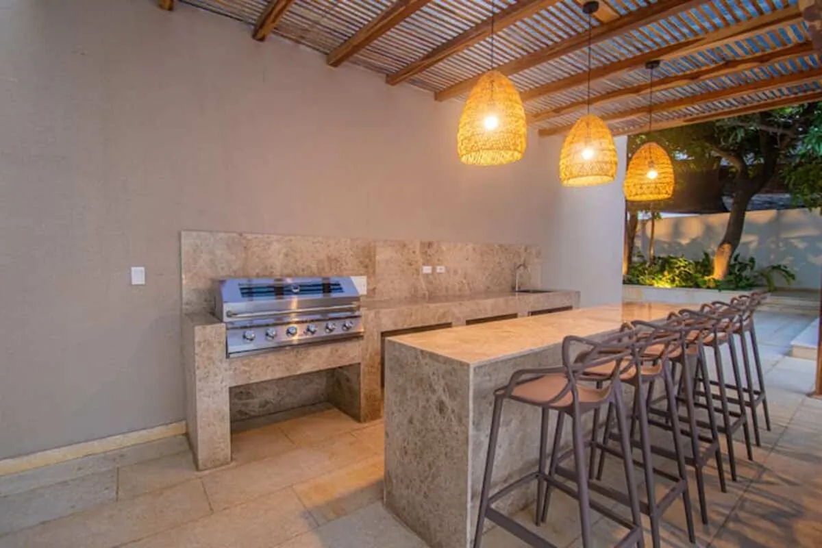 Outdoor kitchen bar with stone island and woven pendant lights